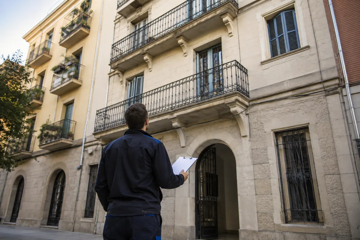 Ilustración de un operario observando desde el suelo los balcones de una fachada